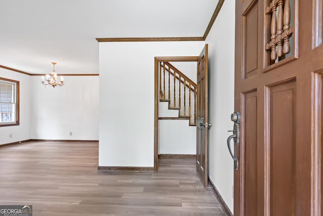 foyer entrance featuring ornamental molding, light wood-type flooring, a notable chandelier, and baseboards