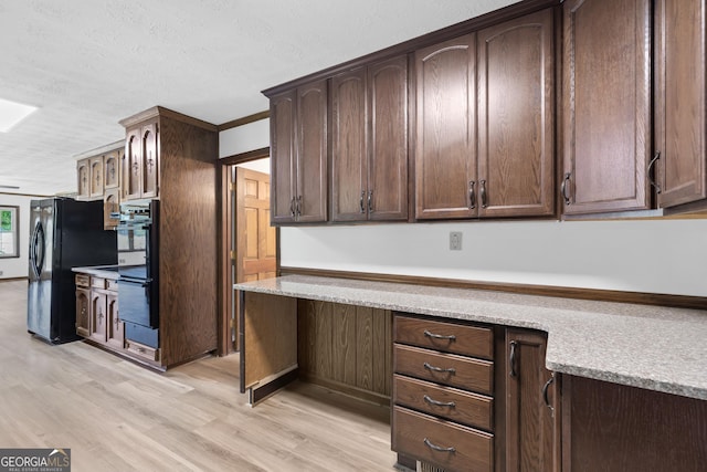 kitchen featuring light stone counters, a textured ceiling, dark brown cabinets, light wood-type flooring, and black appliances