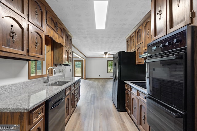 kitchen with light wood finished floors, a sink, a textured ceiling, ceiling fan, and black appliances