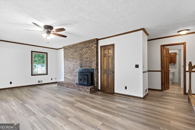 unfurnished living room with a wood stove, visible vents, a textured ceiling, and wood finished floors