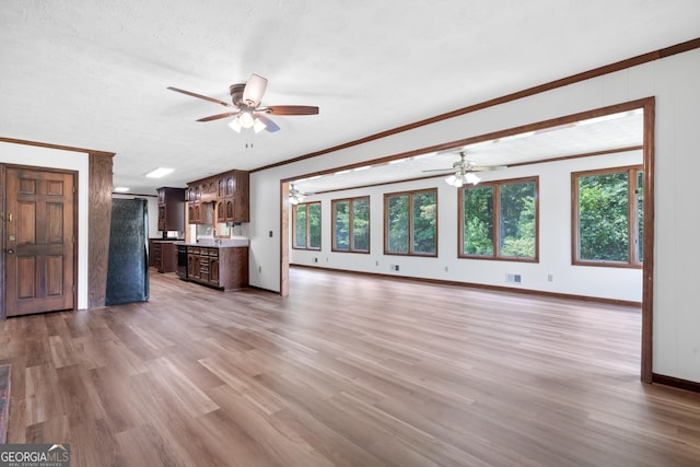 unfurnished living room with baseboards, crown molding, light wood finished floors, and ceiling fan