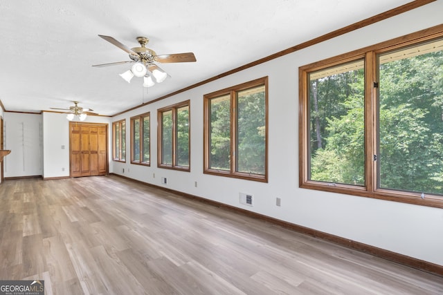 interior space with baseboards, visible vents, light wood-style flooring, ceiling fan, and crown molding