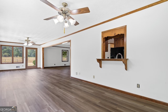 unfurnished living room featuring a ceiling fan, dark wood finished floors, crown molding, and baseboards