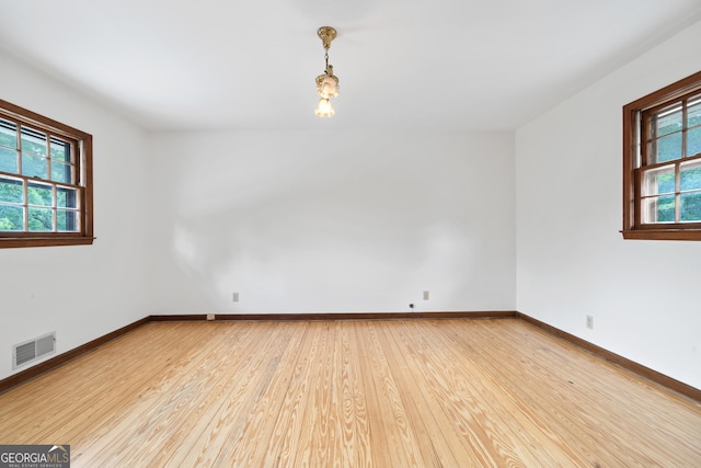 spare room featuring baseboards, visible vents, and light wood-style floors