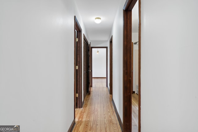 hallway with light wood-type flooring and baseboards