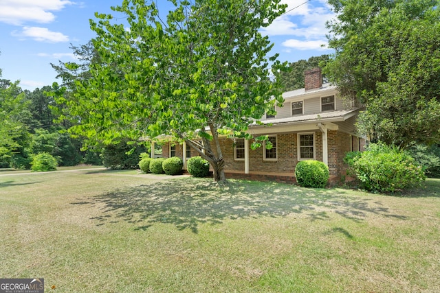 view of front facade with a chimney, a front lawn, and brick siding