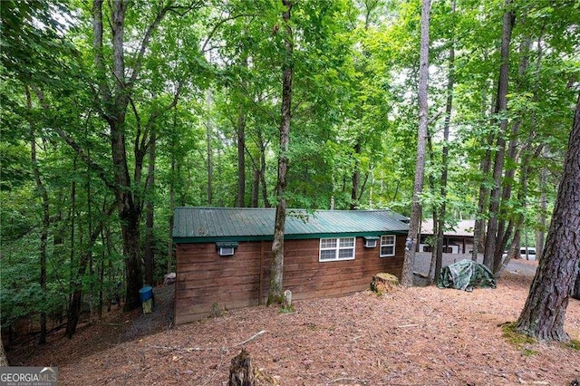 view of property exterior with metal roof and a wooded view