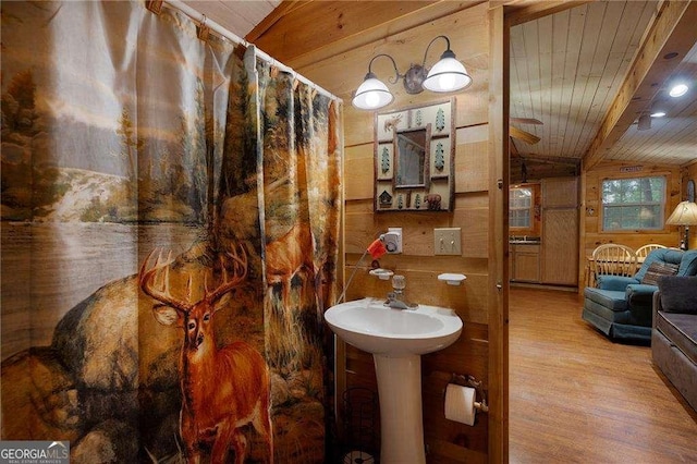 full bath featuring a shower with shower curtain, lofted ceiling with beams, wooden ceiling, wood finished floors, and wood walls