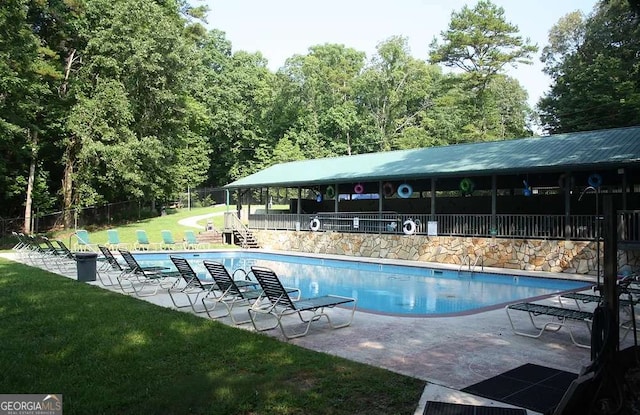 community pool with a yard, a patio area, and fence