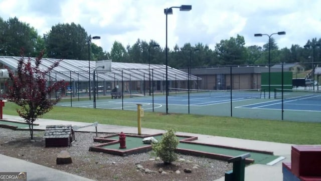 view of home's community featuring a tennis court, fence, and a lawn