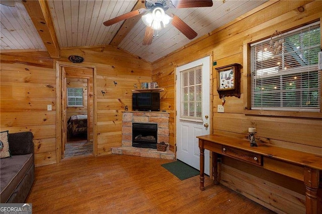 living room featuring a fireplace, lofted ceiling, wooden walls, wood finished floors, and wooden ceiling