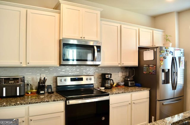 kitchen with white cabinets, tasteful backsplash, stainless steel appliances, and dark stone countertops