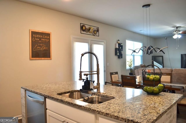 kitchen featuring a sink, white cabinets, open floor plan, light stone countertops, and dishwasher