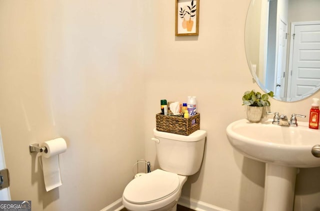 half bathroom featuring a sink, toilet, and baseboards