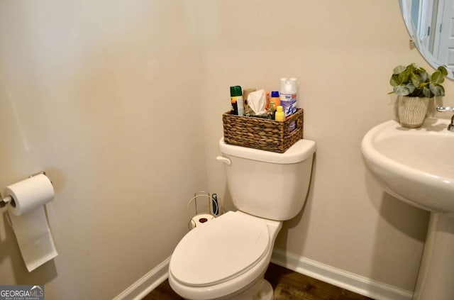 half bath featuring baseboards, toilet, and wood finished floors