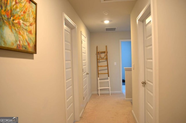 corridor with baseboards, visible vents, and light colored carpet