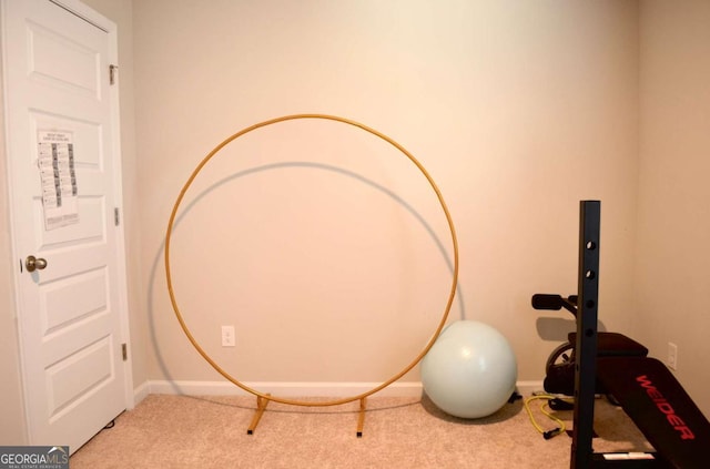 exercise room featuring baseboards and light colored carpet