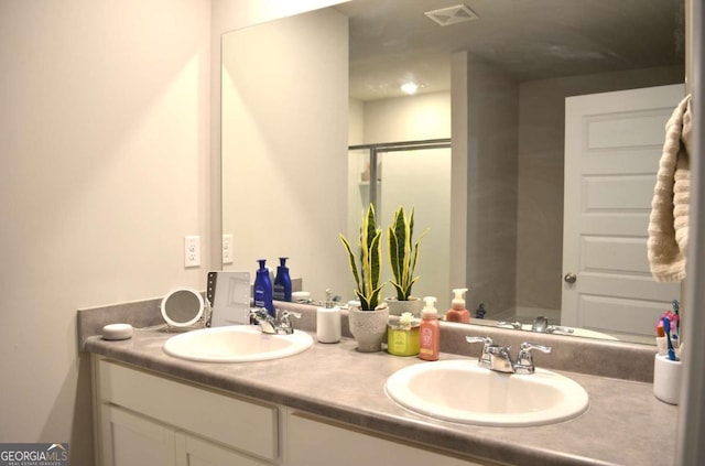 full bathroom with double vanity, a sink, visible vents, and a shower stall