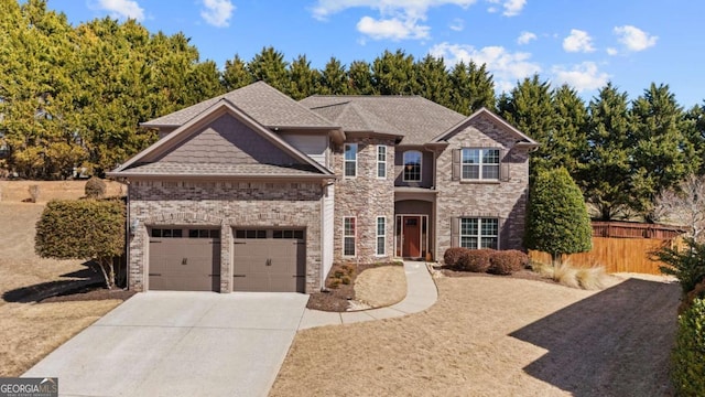 view of front facade with roof with shingles, brick siding, concrete driveway, an attached garage, and fence