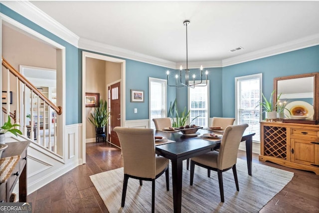 dining space featuring visible vents, wainscoting, dark wood-style floors, crown molding, and a notable chandelier