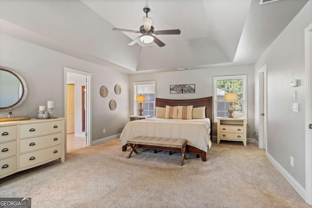 bedroom featuring a tray ceiling, light carpet, visible vents, and baseboards