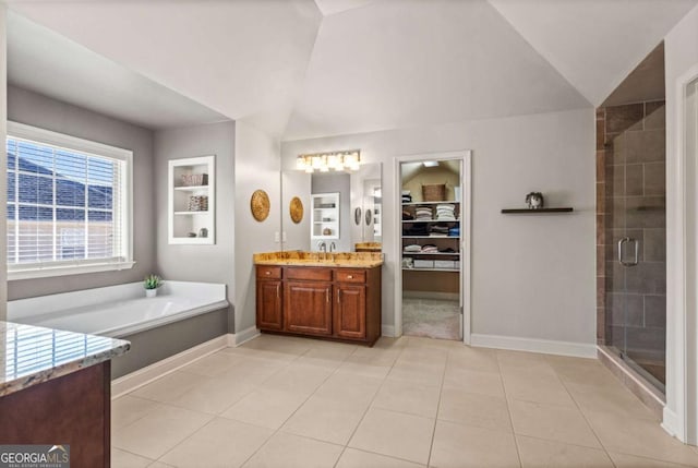 full bath with lofted ceiling, vanity, tile patterned floors, a stall shower, and a walk in closet