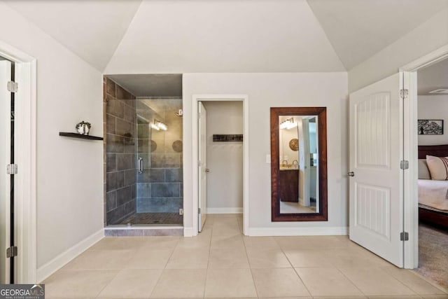 ensuite bathroom featuring lofted ceiling, a shower stall, tile patterned flooring, and ensuite bathroom