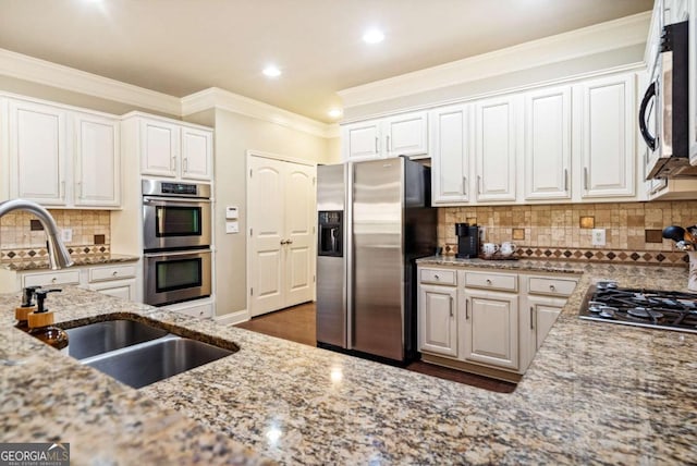 kitchen with ornamental molding, stainless steel appliances, light stone counters, and a sink