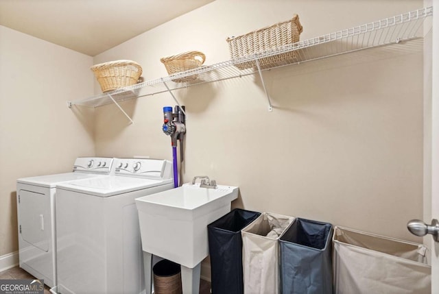 laundry area with laundry area, washing machine and dryer, baseboards, and a sink