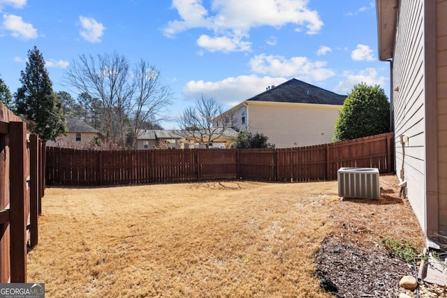 view of yard with a fenced backyard and central AC unit