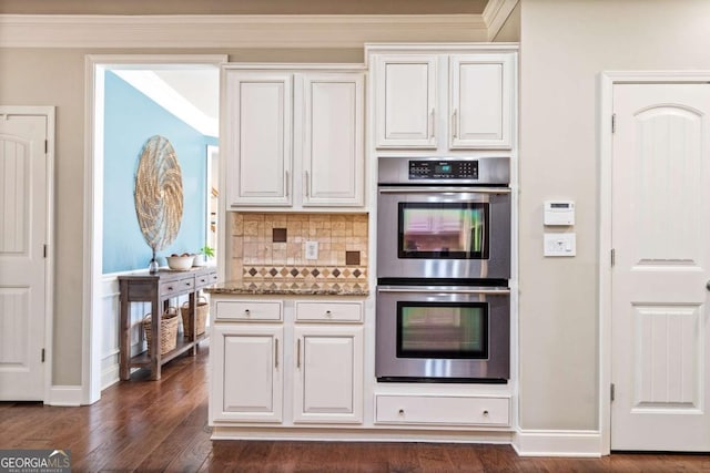 kitchen featuring double oven, white cabinetry, light stone countertops, tasteful backsplash, and dark wood finished floors