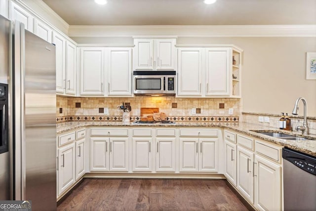 kitchen featuring dark wood finished floors, light stone counters, appliances with stainless steel finishes, crown molding, and a sink