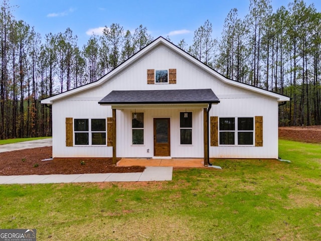 modern farmhouse style home featuring a front yard and roof with shingles