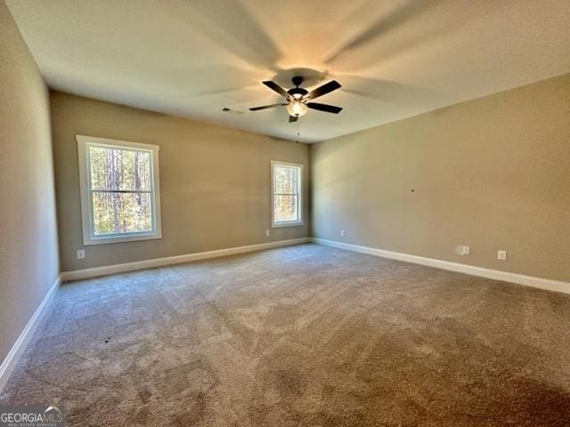 spare room featuring carpet floors, visible vents, baseboards, and a ceiling fan