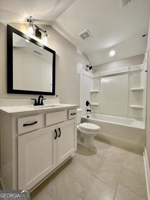 bathroom featuring visible vents, lofted ceiling, toilet, vanity, and washtub / shower combination