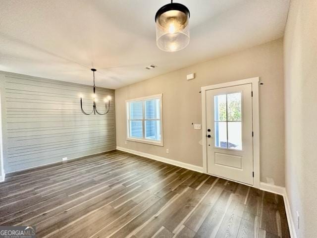 interior space with baseboards, a chandelier, and dark wood-style flooring