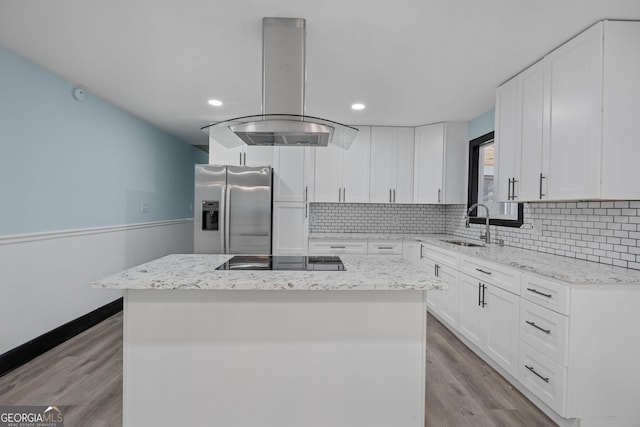 kitchen featuring a center island, a sink, island range hood, stainless steel fridge, and black electric cooktop