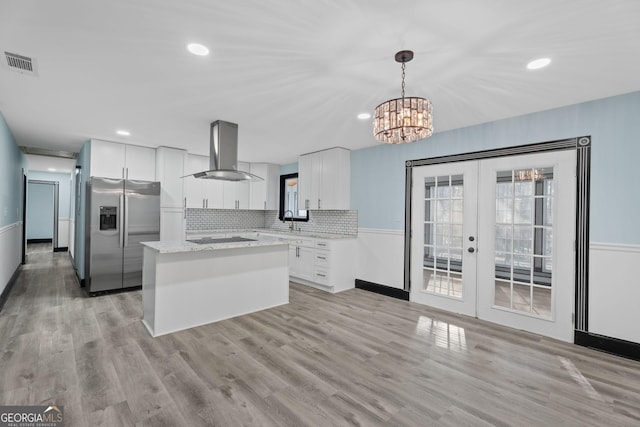 kitchen with black cooktop, visible vents, white cabinets, stainless steel fridge, and exhaust hood