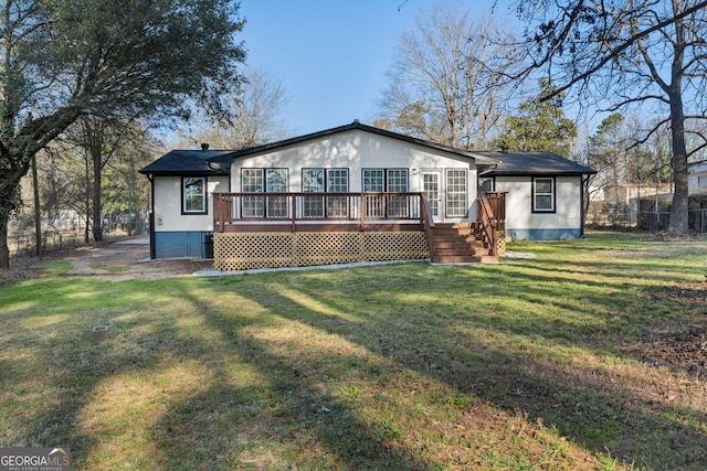 back of house featuring a lawn, a wooden deck, and fence