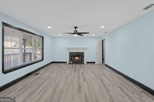 unfurnished living room featuring recessed lighting, visible vents, a high end fireplace, wood finished floors, and baseboards