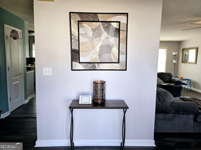 hall featuring baseboards, dark wood-style flooring, and a textured ceiling