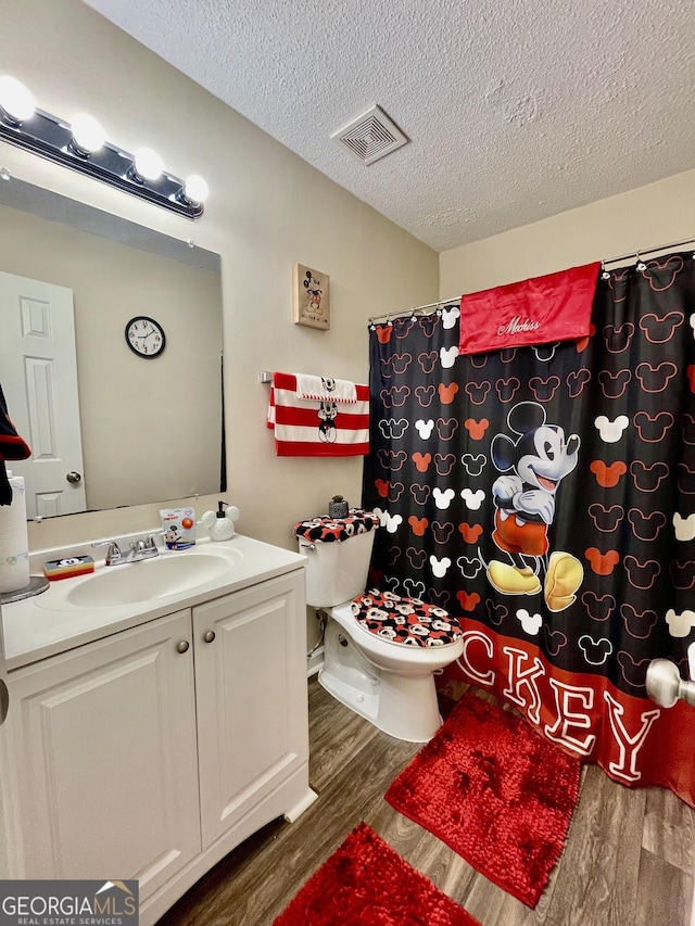 bathroom with visible vents, toilet, wood finished floors, a textured ceiling, and vanity