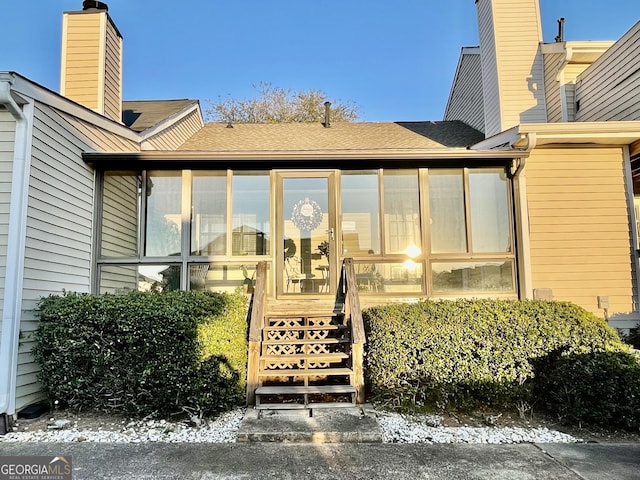 doorway to property featuring roof with shingles and a chimney