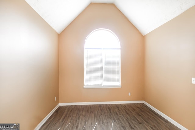 spare room with lofted ceiling, baseboards, and wood finished floors