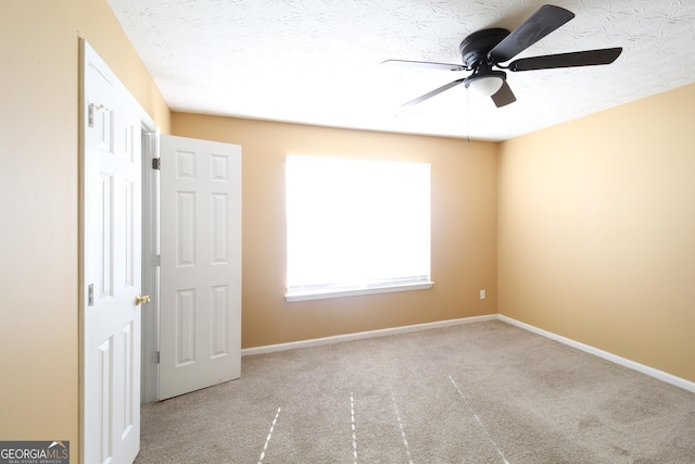 empty room with a ceiling fan, carpet, a textured ceiling, and baseboards