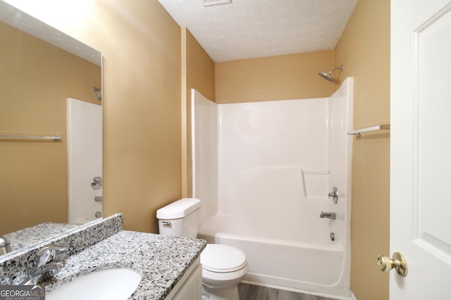 full bath with a textured ceiling, toilet, shower / bath combination, wood finished floors, and vanity