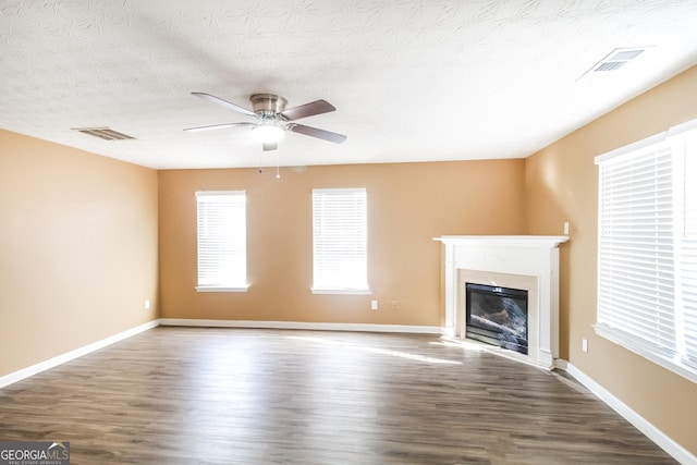 unfurnished living room with wood finished floors, a glass covered fireplace, and visible vents