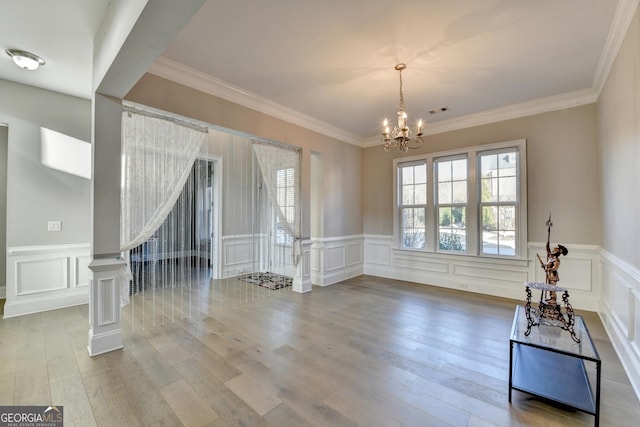 interior space with a decorative wall, stairway, wood finished floors, and an inviting chandelier