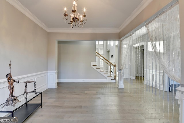 foyer with a chandelier, crown molding, and wood finished floors