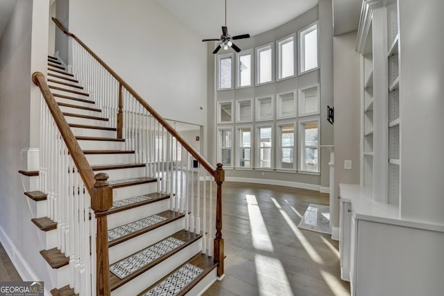 entrance foyer featuring a ceiling fan, baseboards, a towering ceiling, and hardwood / wood-style floors